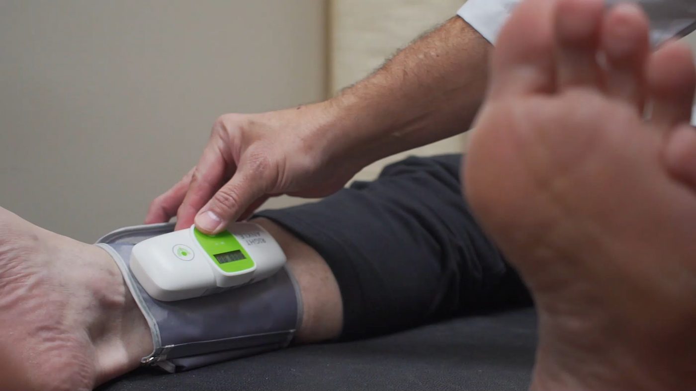 A clinician placing a wireless Smart-ABI cuff on a patient at the point of care